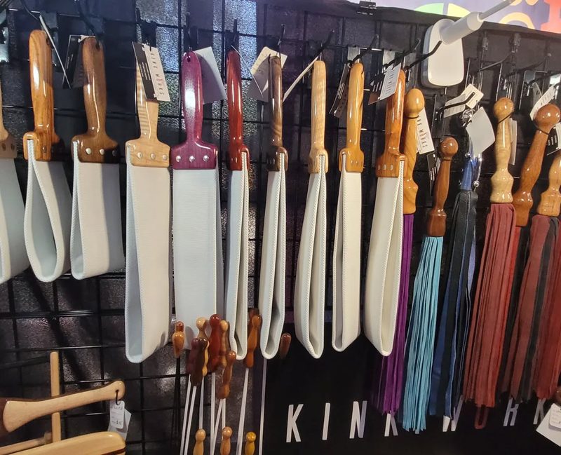 Floggers and leather straps hanging on a display wall