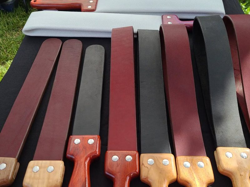 Leather straps with wooden handles laid out on a table